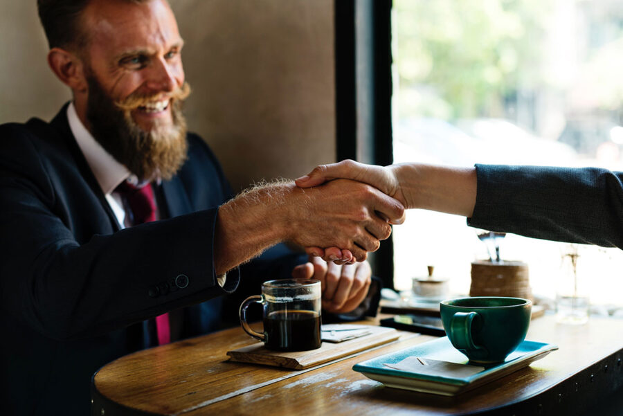 man with mustache shakes hands but someone
