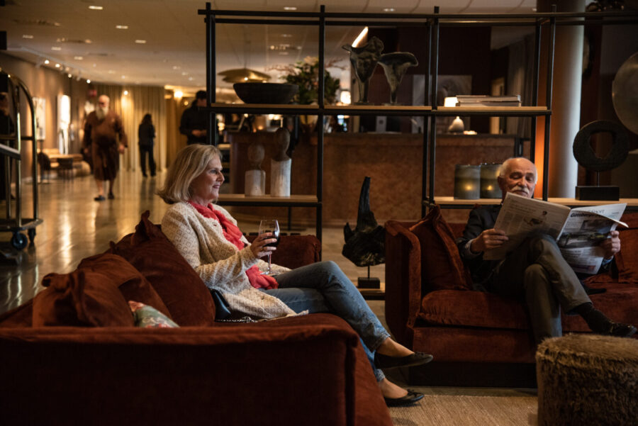 woman drinking wine and man reading newspaper in the lobby